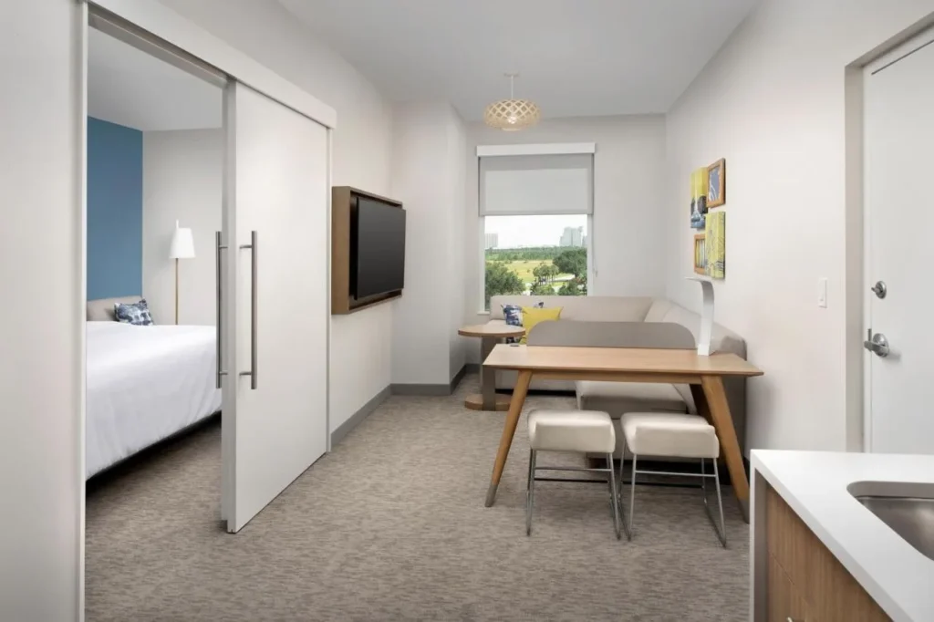 Suite de un dormitorio con sofá, mesa y puerta corredera al dormitorio, Element Orlando