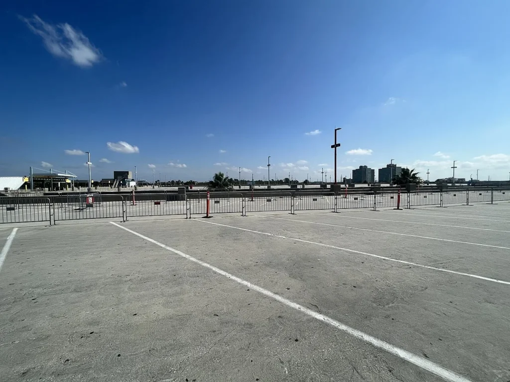 Open-air parking level at Universal Orlando's main garage with crowd barriers under a blue sky