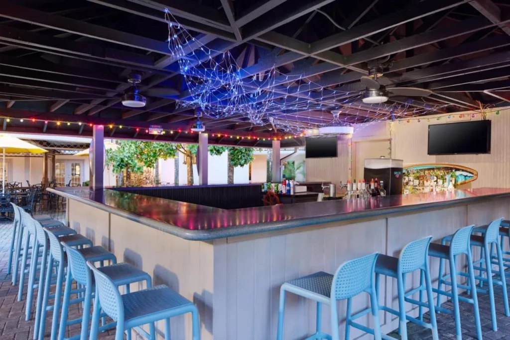 Open-air pool bar with string lights and blue stools at Staybridge Suites Orlando Royale Parc