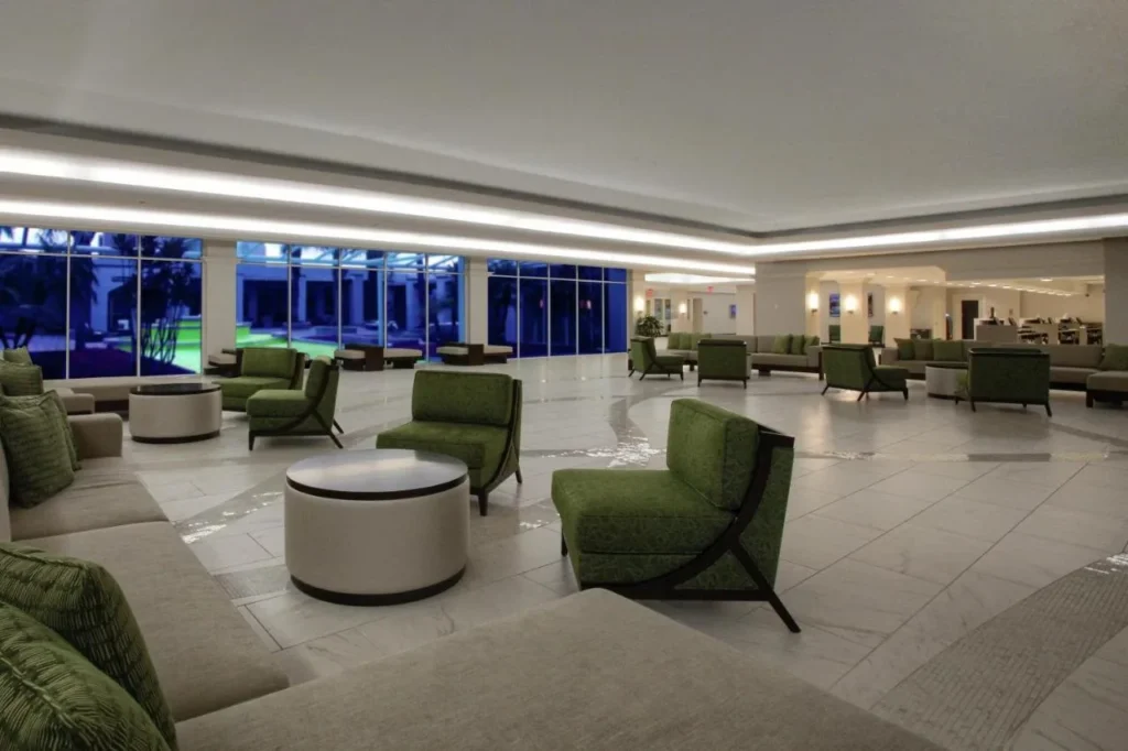 Sal&oacute;n de vest&iacute;bulo abierto con sillones verdes y mesas redondas, DoubleTree at the Entrance to Universal