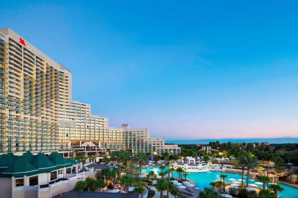 Orlando World Center Marriott towers above the palm-lined Falls Pool at dusk