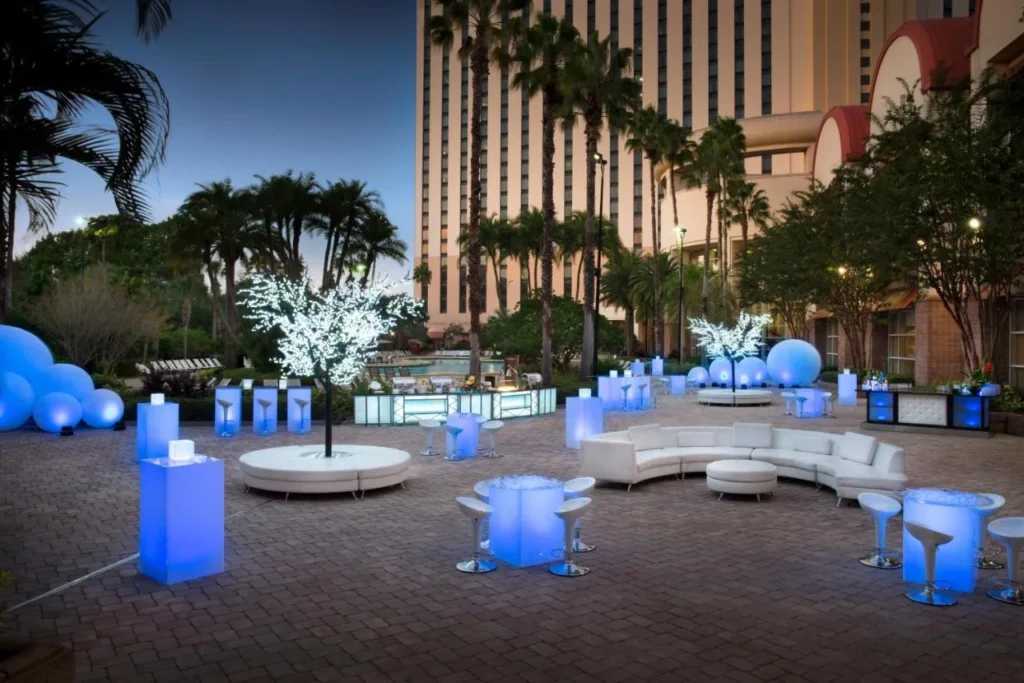 Patio para eventos al aire libre con mesas de cóctel brillantes y asientos de salón blancos en Rosen Centre Hotel