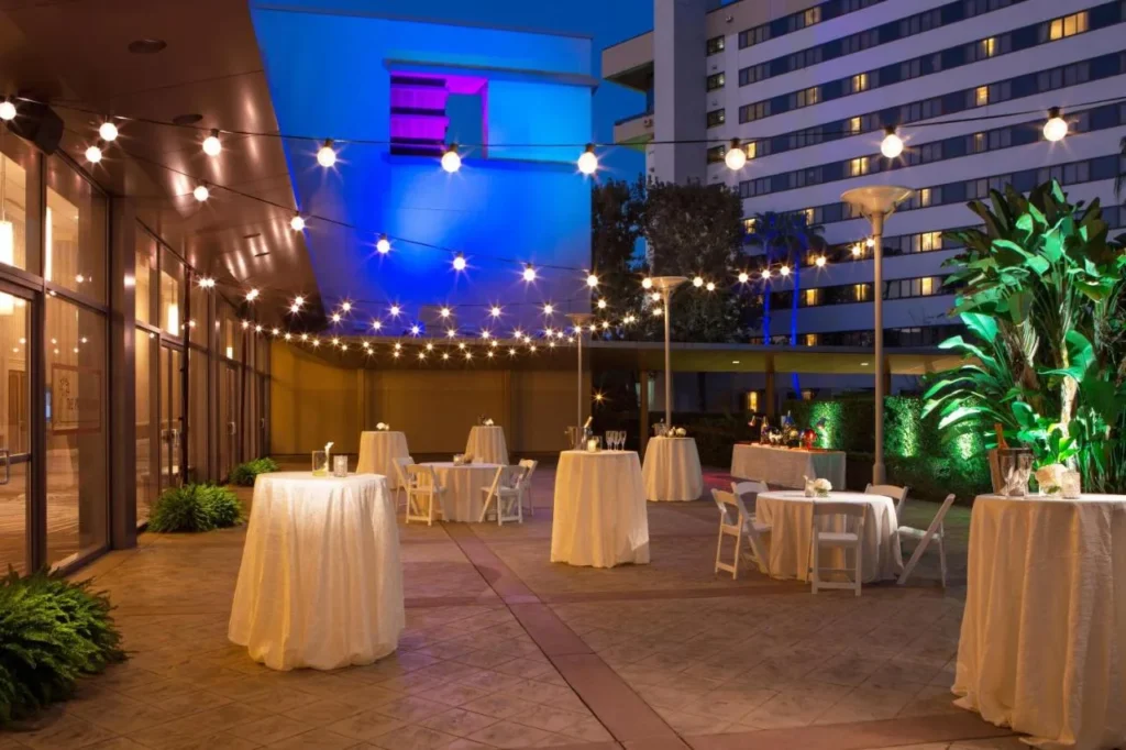 Terraza para eventos al aire libre con luces de cuerda y mesas de cóctel en Hilton Orlando Lake Buena Vista