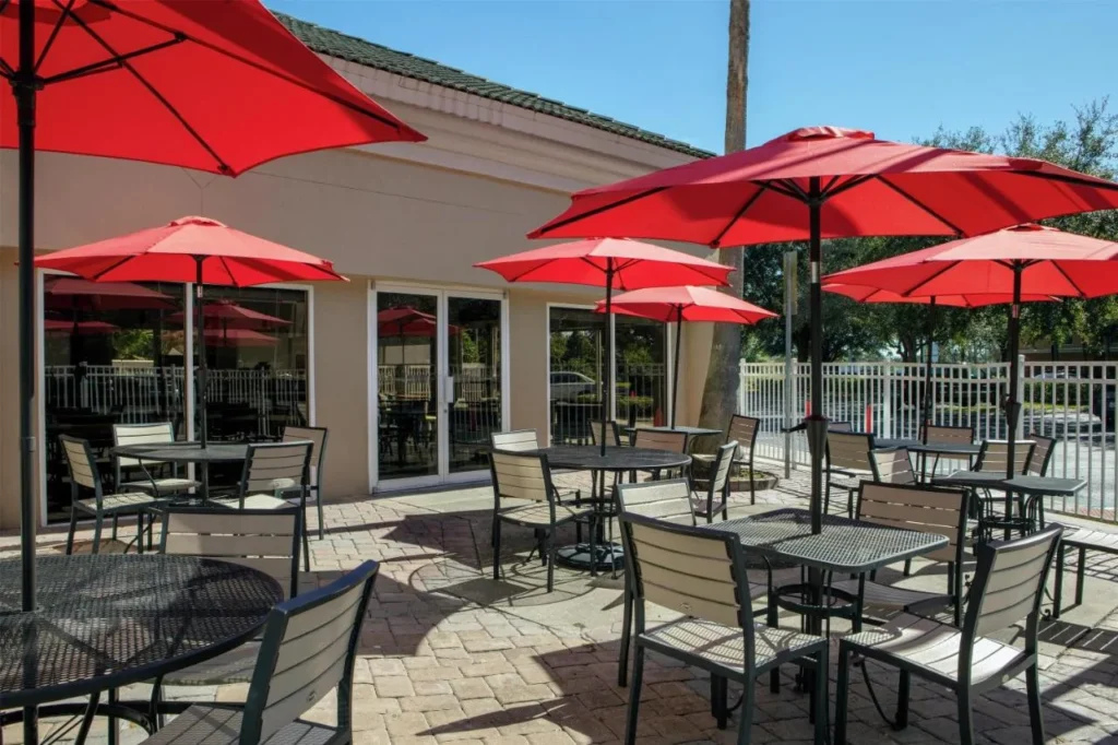 Outdoor patio tables under red umbrellas at Hampton Inn Orlando/Lake Buena Vista