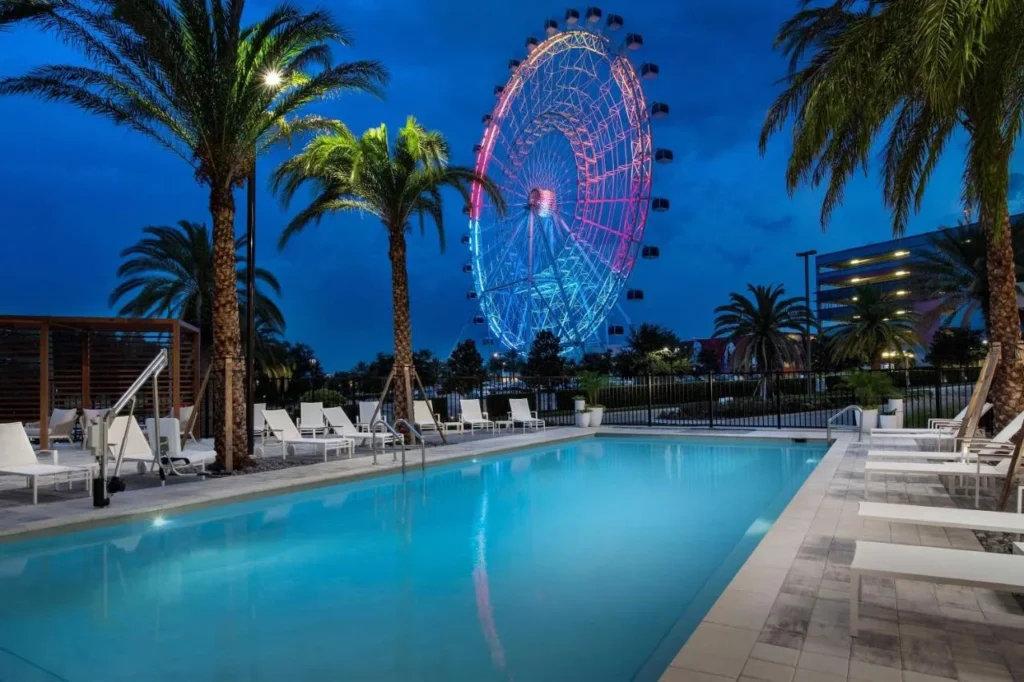 Piscina al aire libre y tumbonas por la noche con The Wheel detr&aacute;s, Element Orlando Universal Blvd.