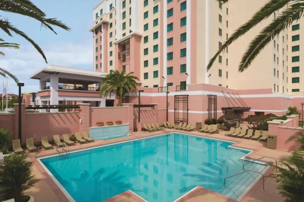 Piscina al aire libre y tumbonas debajo de la torre del hotel en Embassy Suites Lake Buena Vista South