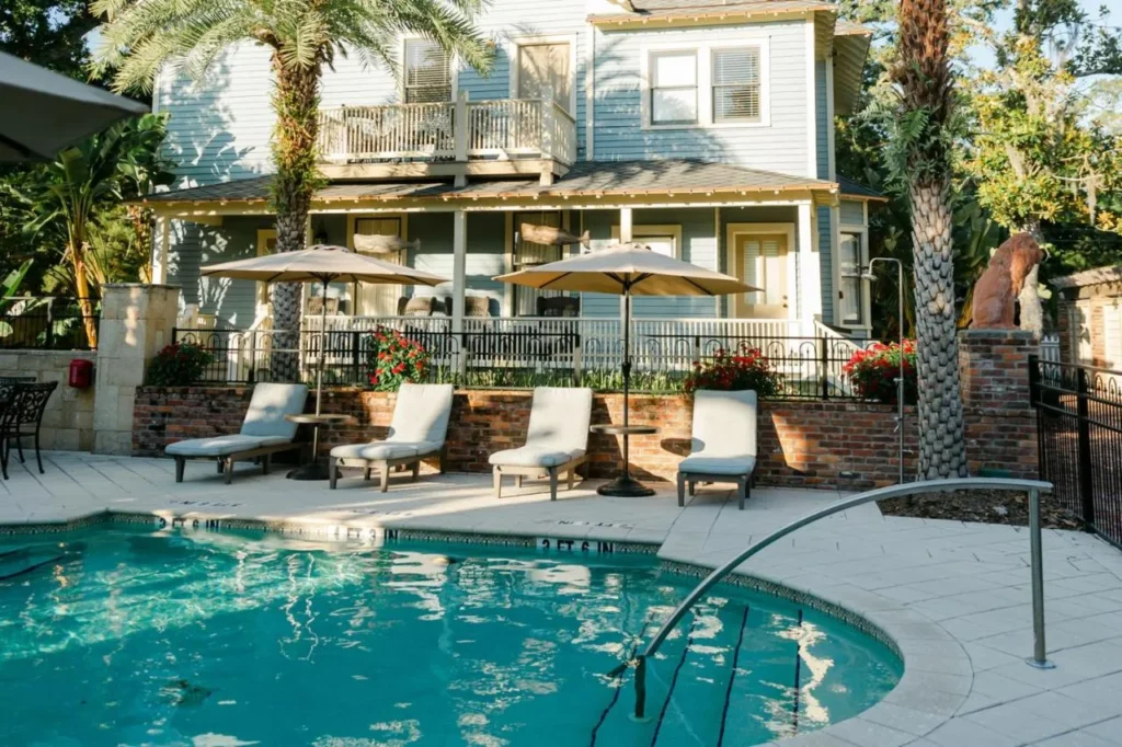 Outdoor pool and loungers beside a historic house at The Collector Inn & Gardens