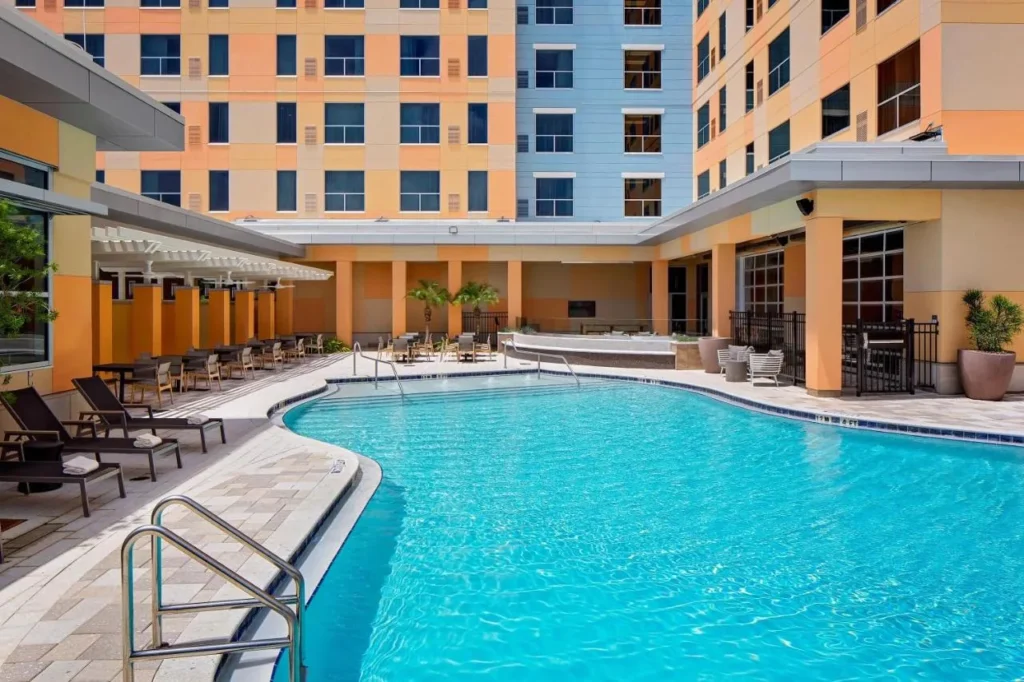 Piscina al aire libre curva y tumbonas en el Courtyard de Hyatt House across from Universal Orlando Resort