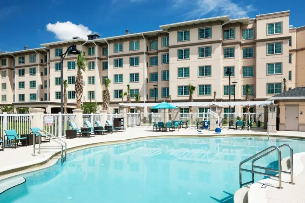 Piscina al aire libre con ascensor, tumbonas y el ala de invitados de cinco pisos en Residence Inn Near Universal Orlando