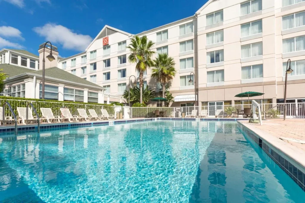 Piscina al aire libre y tumbonas junto al edificio Hilton Garden Inn Daytona Beach Airport