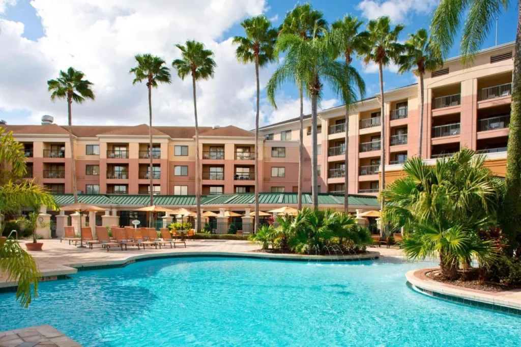 Outdoor pool and tall palms at Courtyard Orlando Lake Buena Vista in the Marriott Village