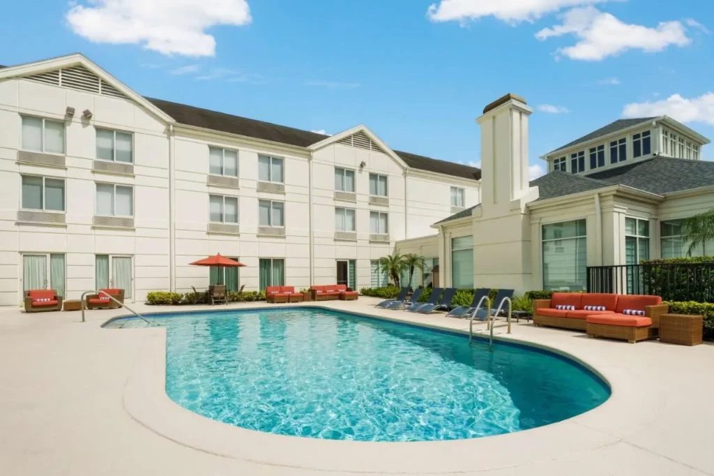 Piscina al aire libre y edificio blanco de tres pisos en Hilton Garden Inn Orlando North/Lake Mary