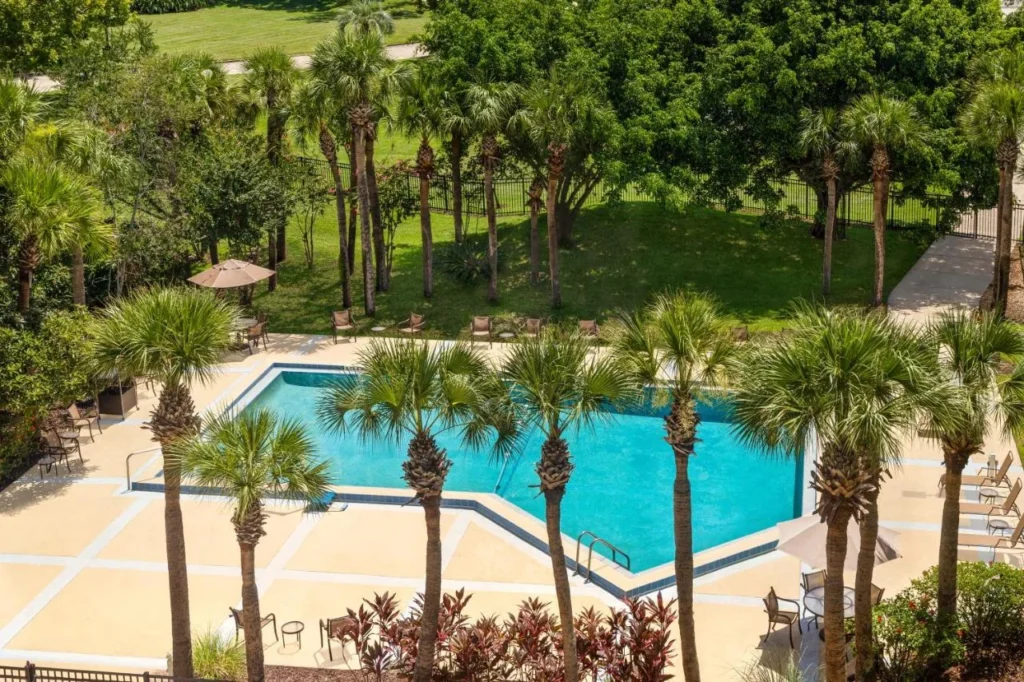 Piscina al aire libre rodeada de palmeras y c&eacute;sped visto desde arriba en el Holiday Inn Orlando International Airport