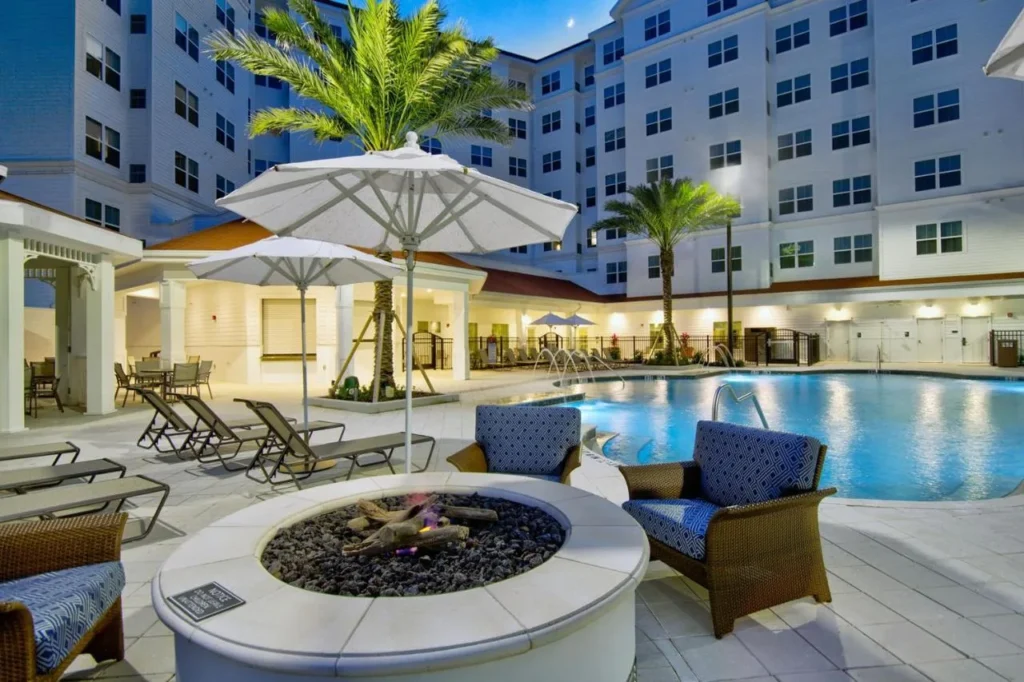 Piscina al aire libre con fogata, tumbonas y sombrillas en el Residence Inn Flamingo Crossings