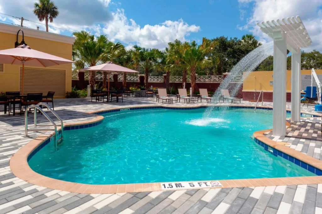 Outdoor pool with a water fountain and palms at Courtyard by Marriott DeLand Historic Downtown