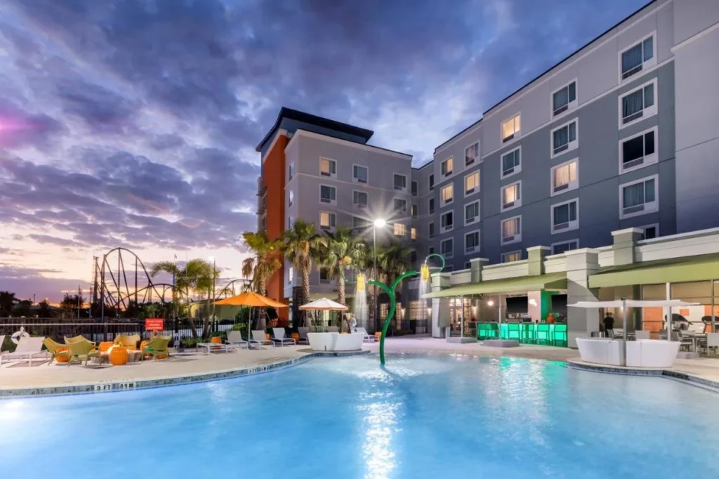 Outdoor pool with a water spray feature at dusk at TownePlace Suites Orlando at SeaWorld