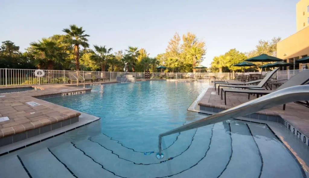 Outdoor pool with entry steps and green umbrellas at Hyatt Place Orlando/Lake Buena Vista