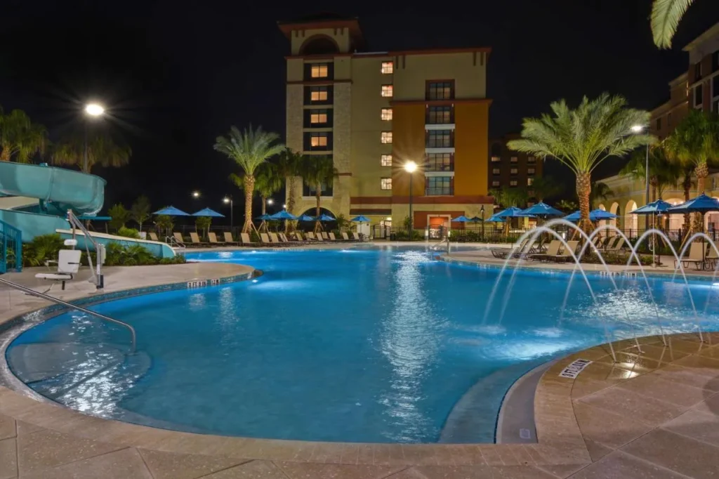 Piscina al aire libre con chorros de fuente y un tobogán por la noche en Home2 Suites Flamingo Crossings