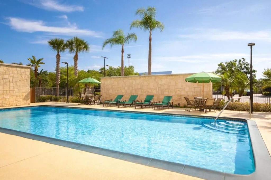 Outdoor pool with green umbrellas and loungers at Fairfield Inn & Suites Orlando Kissimmee/Celebration