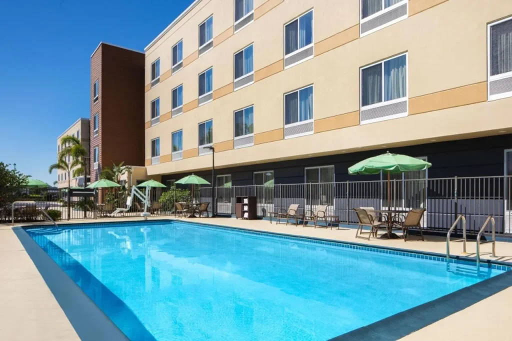 Piscina al aire libre con sombrillas verdes al lado del edificio en Fairfield Inn & Suites Orlando Kissimmee/Celebration
