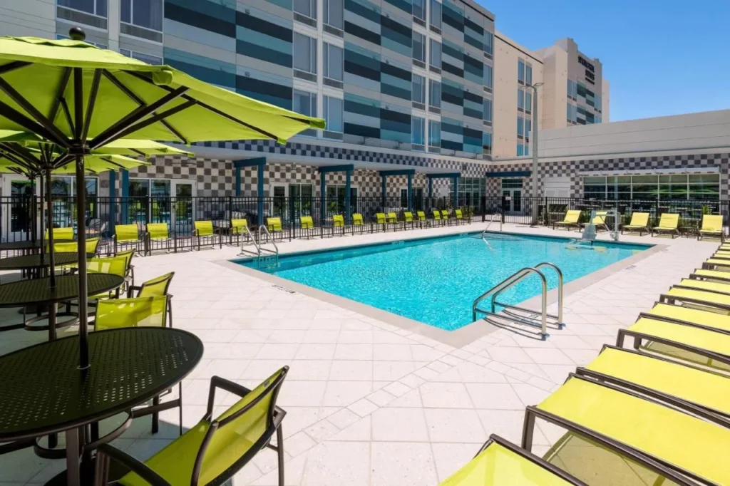 Piscina al aire libre con tumbonas y sombrillas de color verde lima en SpringHill Suites by Marriott Lakeland
