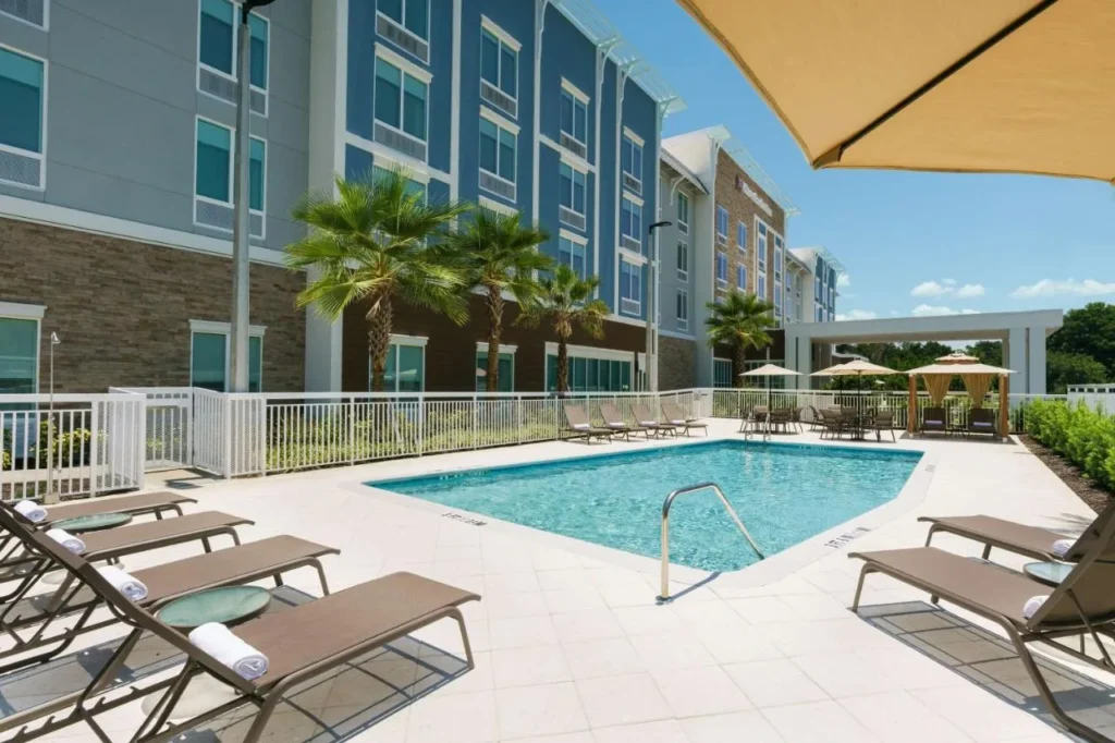Outdoor pool with lounge chairs and a shade umbrella at Hilton Garden Inn Apopka City Center