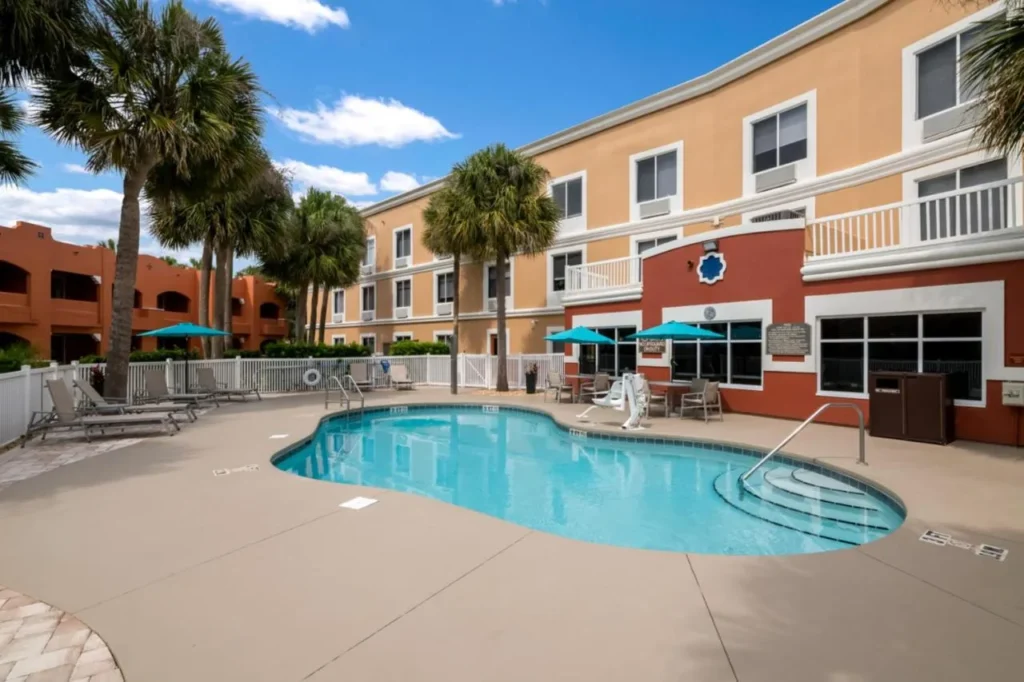 Piscina al aire libre con tumbonas y palmeras en Holiday Inn Express & Suites The Villages