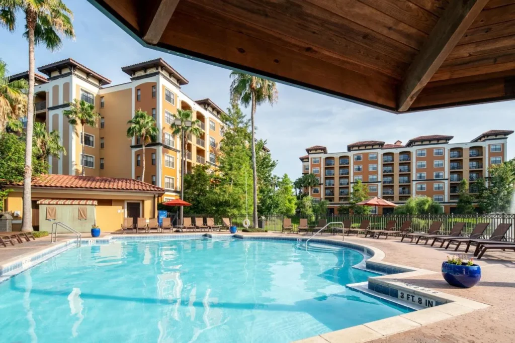 Piscina al aire libre con tumbonas y palmeras debajo de los edificios de condominios en Floridays Resort Orlando