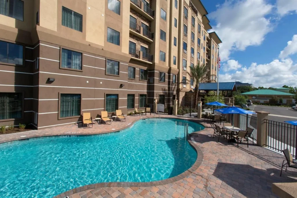Piscina al aire libre con tumbonas y sombrillas junto a Staybridge Suites Orlando at SeaWorld