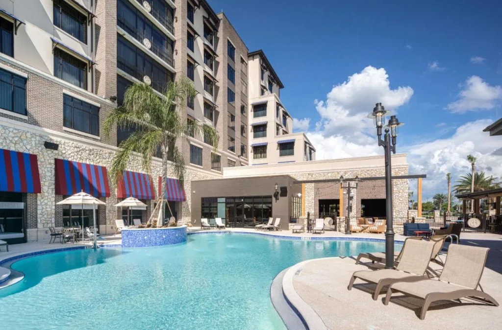 Piscina al aire libre con tumbonas y toldos a rayas junto al edificio The Brownwood Hotel & Spa
