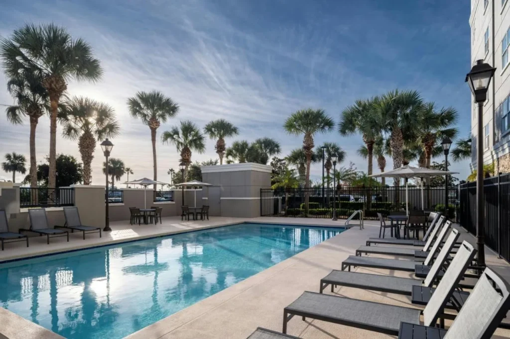 Outdoor pool with lounge chairs and tall palm trees at Residence Inn by Marriott Melbourne