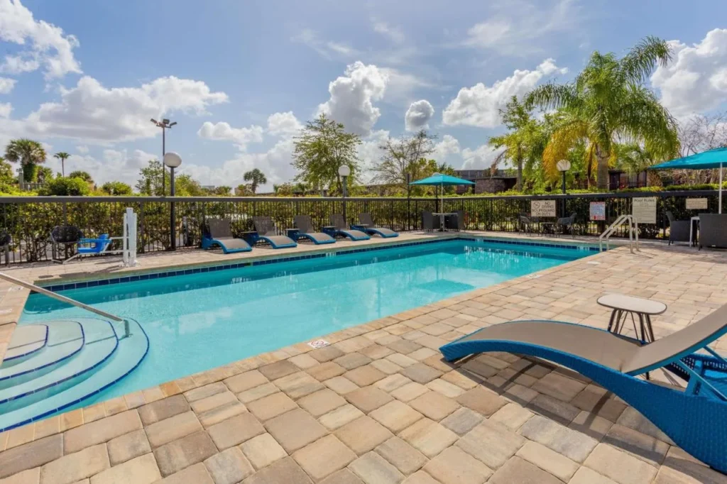 Outdoor pool with lounge chairs and umbrellas at Hampton Inn & Suites Orlando International Drive North