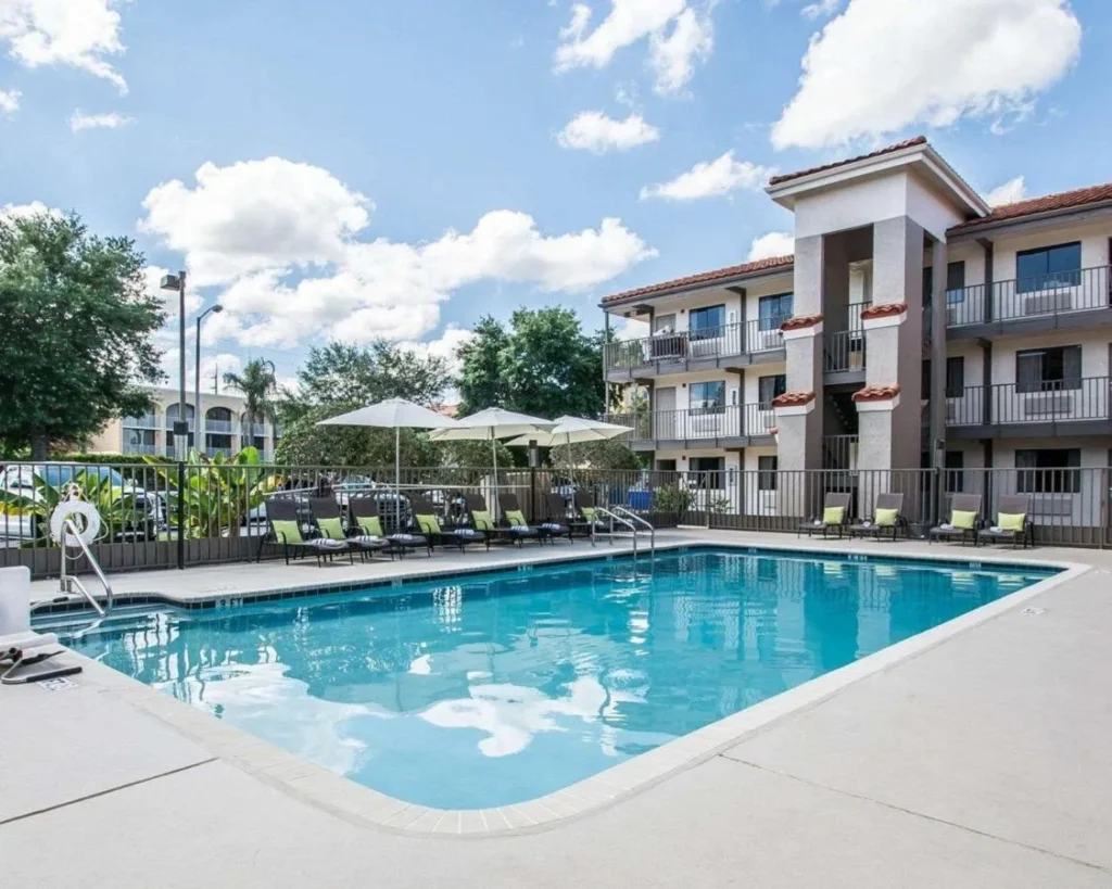 Piscina al aire libre con tumbonas y sombrillas blancas en Quality Inn & Suites By the Parks