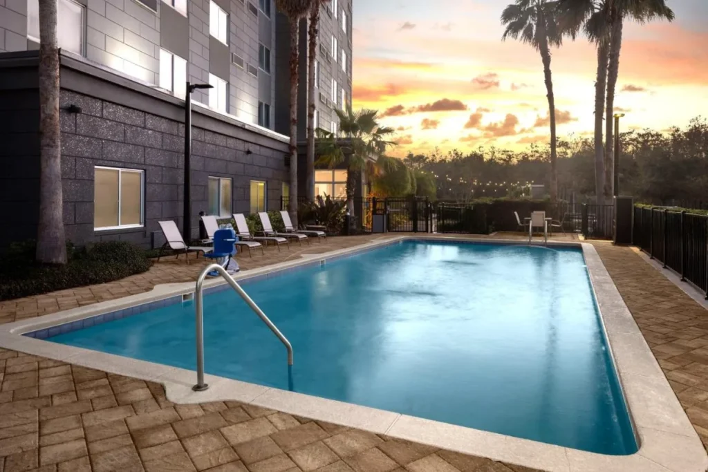 Piscina al aire libre con tumbonas al atardecer en Courtyard Orlando South/Grande Lakes Área