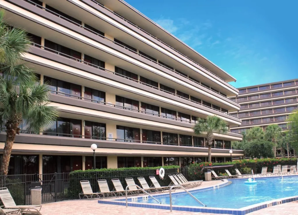Outdoor pool with lounge chairs beside the balconied building at Rosen Inn at Pointe Orlando