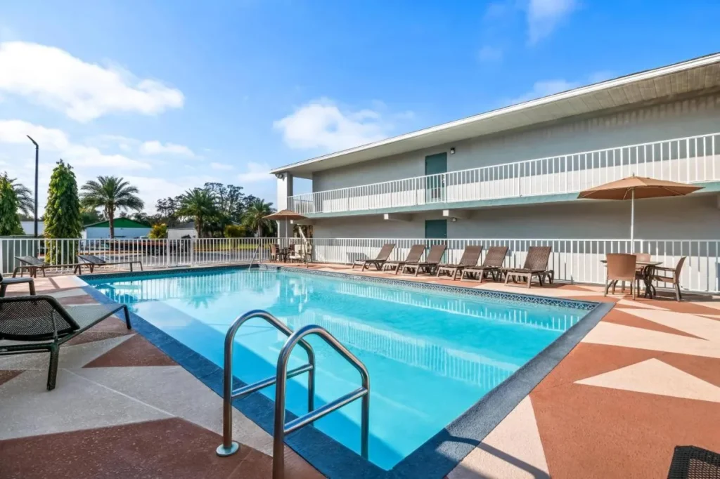 Outdoor pool with lounge chairs beside the two-story Quality Inn Orange City building