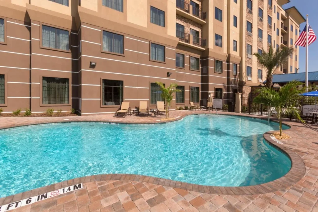 Outdoor pool with lounge chairs in front of the Staybridge Suites Orlando at SeaWorld building