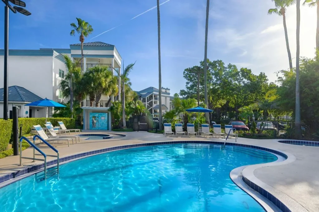 Outdoor pool with lounge chairs, palms and a villa building at Marriott's Imperial Palms Villas