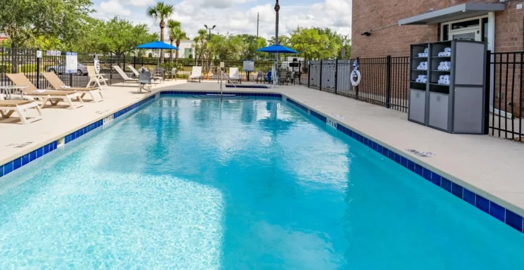 Outdoor pool with loungers and blue umbrellas at Holiday Inn Express Orange City