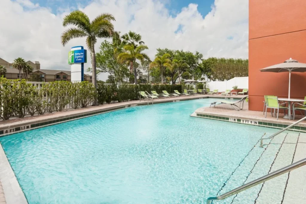 Outdoor pool with loungers and palm trees at Holiday Inn Express & Suites Nearest Universal Orlando