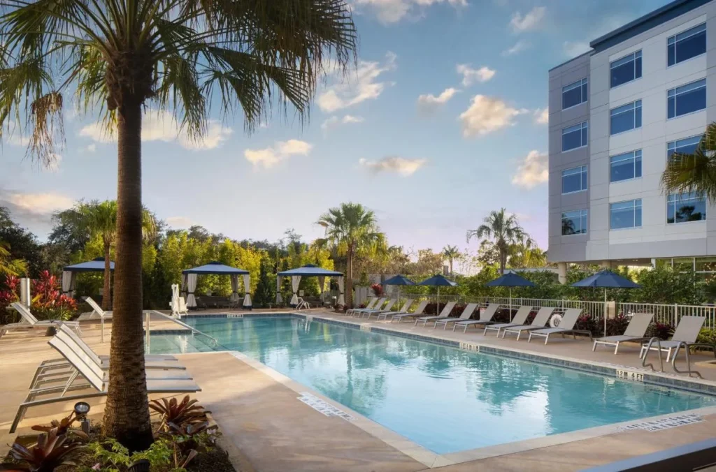 Piscina al aire libre con tumbonas, sombrillas y cabañas blancas junto a The Celeste Hotel cerca de UCF