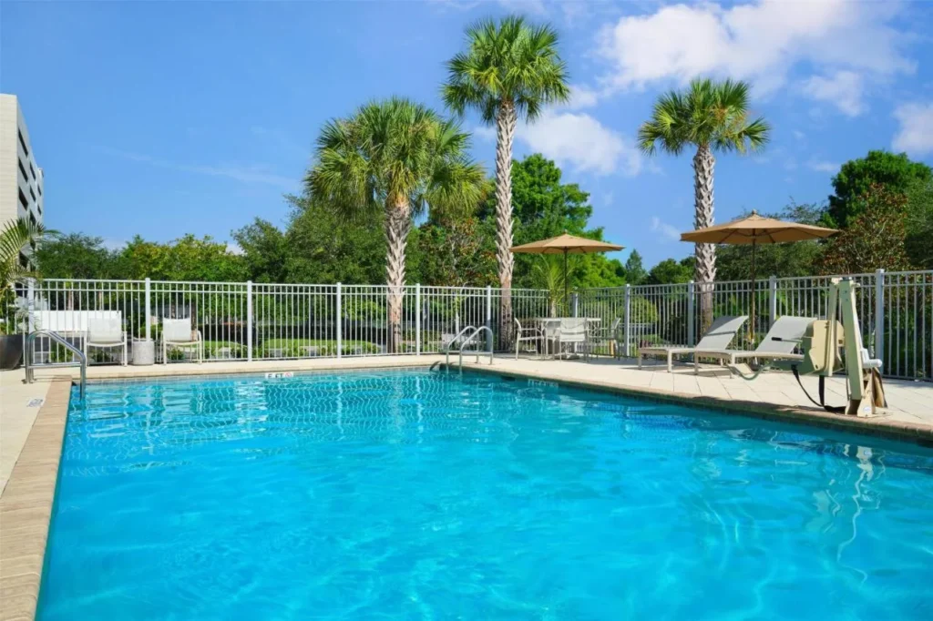 Outdoor pool with palm trees and umbrellas at Hampton Inn & Suites Orlando Downtown South