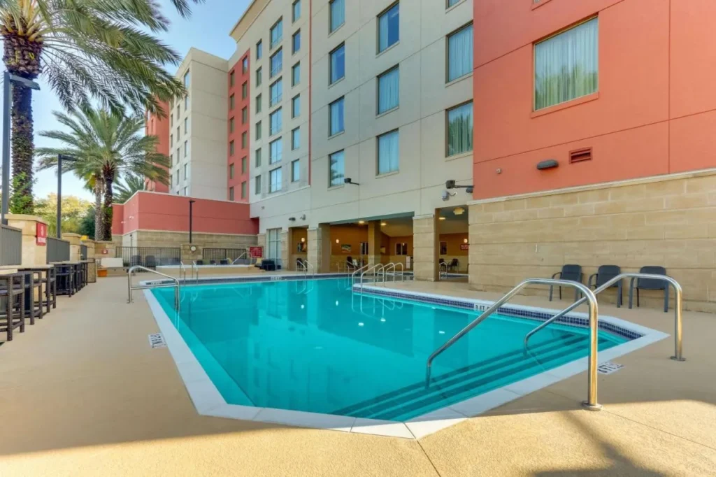 Piscina al aire libre con palmeras al lado del hotel en Drury Inn & Suites near Universal