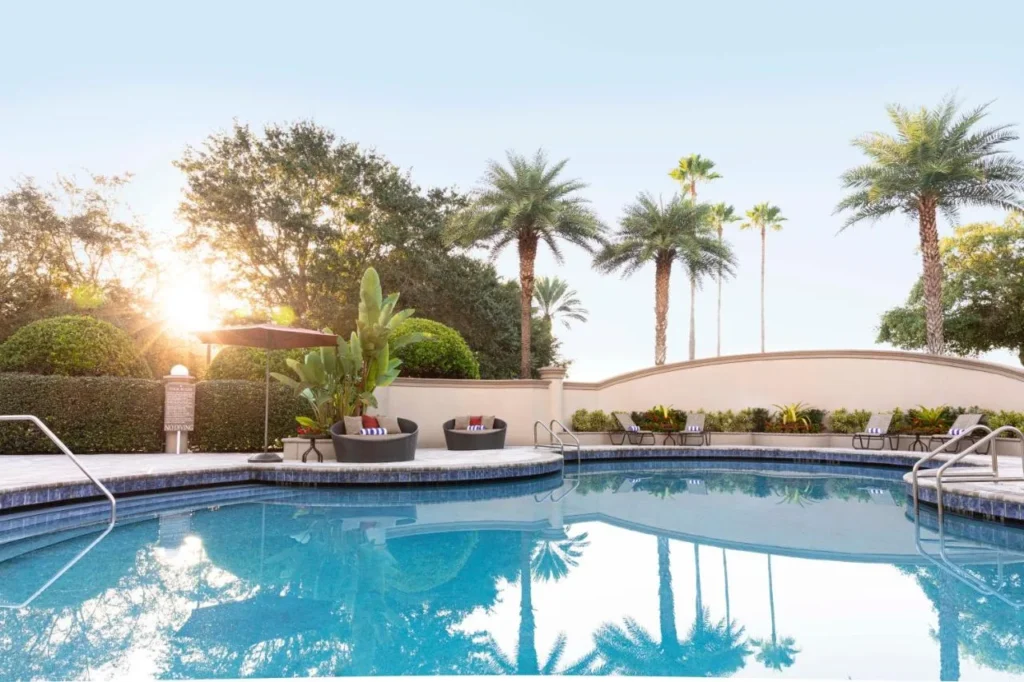 Piscina al aire libre con palmeras, tumbonas y camas de mimbre en Buena Vista Suites Orlando