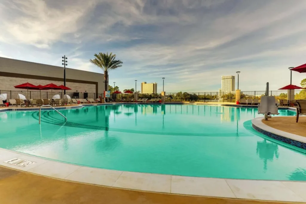 Outdoor pool with red umbrellas and loungers at Drury Plaza Hotel Orlando Disney Springs Area