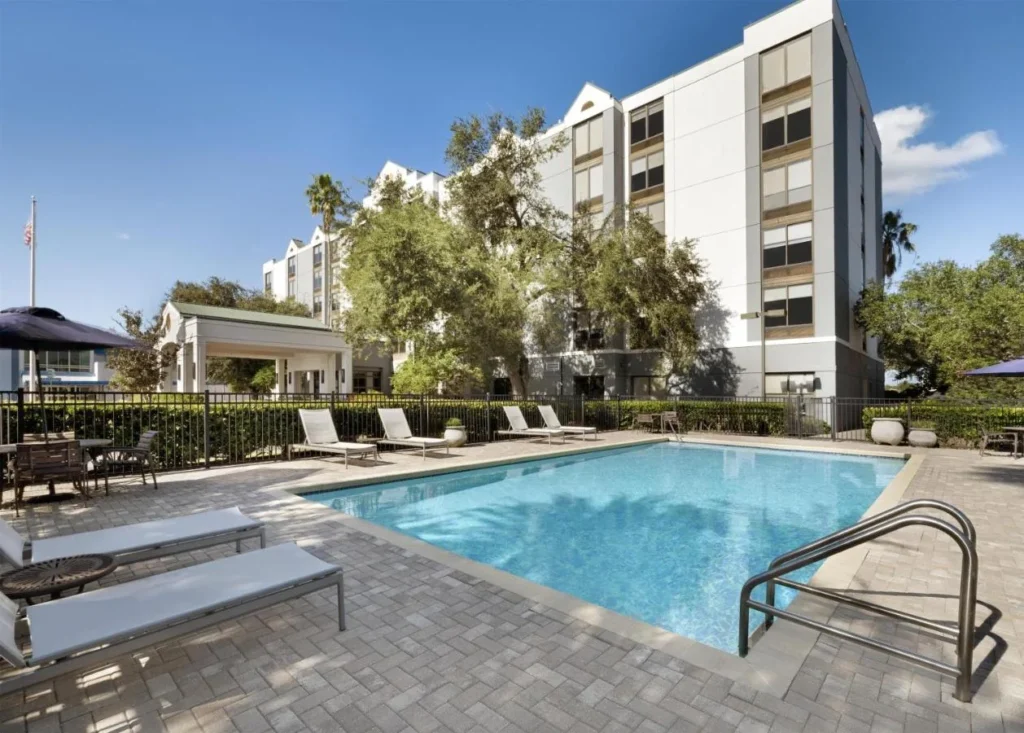 Piscina al aire libre con tumbonas blancas junto al edificio Hyatt Place Lakeland Center