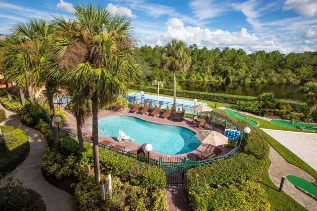 Overhead view of a fenced pool, loungers, mini golf and a lake at Westgate Leisure Resort