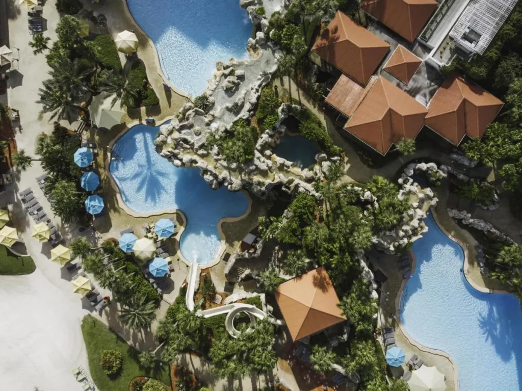 Vista a&eacute;rea de las piscinas Hyatt Regency Grand Cypress, grutas de roca, tobog&aacute;n acu&aacute;tico y cubierta de piscina forrada con paraguas