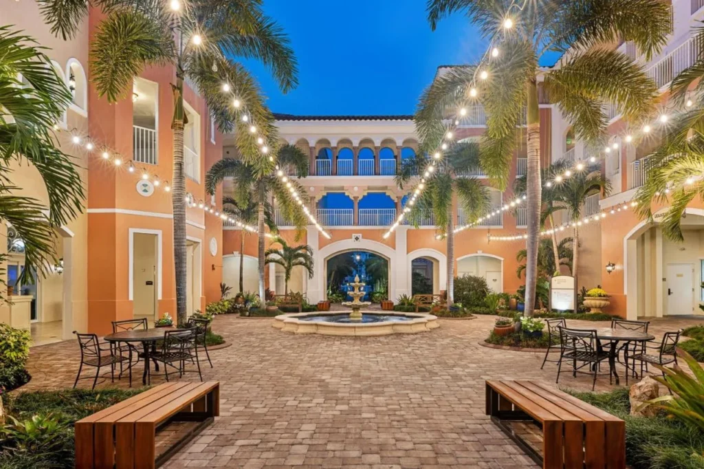 Courtyard bordeado de palmeras con luces de cadena, una fuente y mesas de café en el Marriott's Grande Vista
