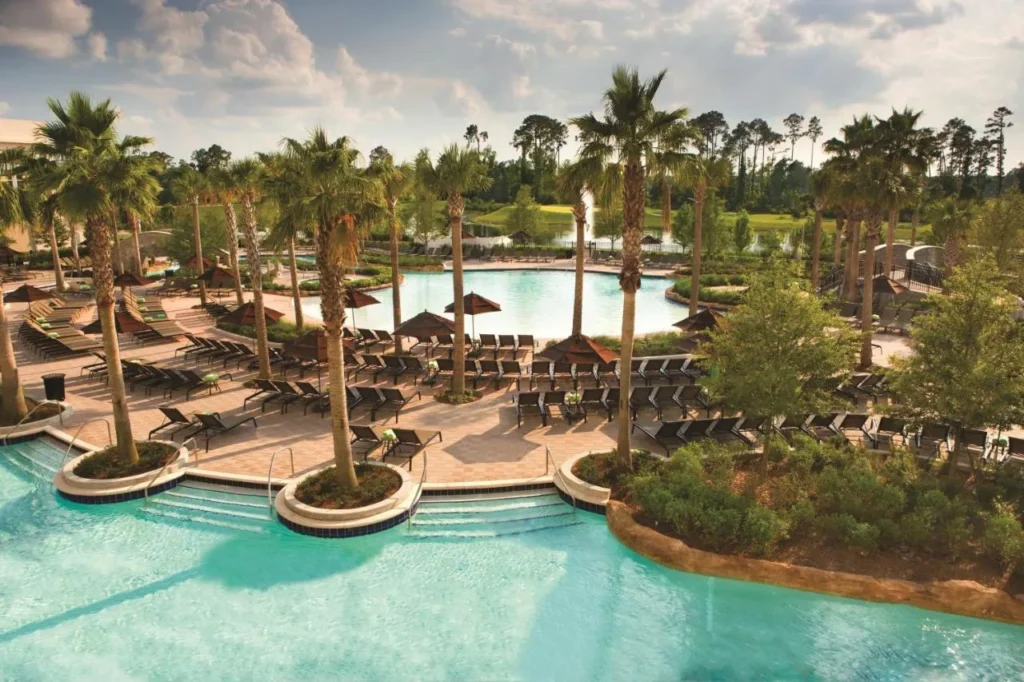 Palm-lined lagoon pool with loungers and a second pool beyond at Signia by Hilton Orlando